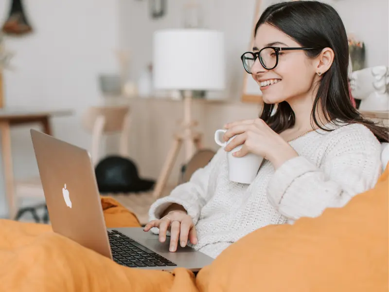 Woman with a laptop computer and a mug in her left hand.